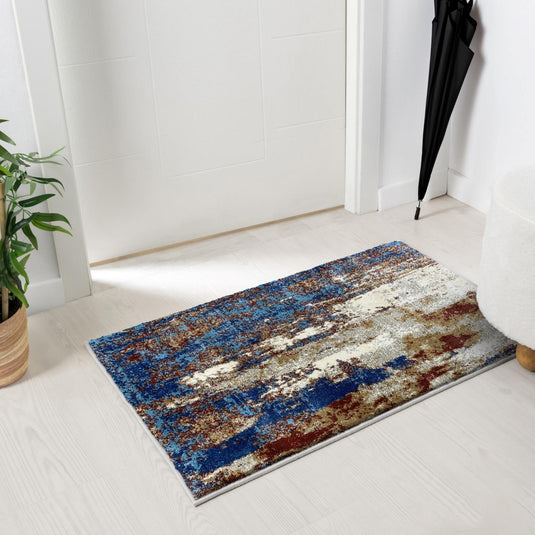 Multicolored doormat on a white floor with a plant and umbrella in the background