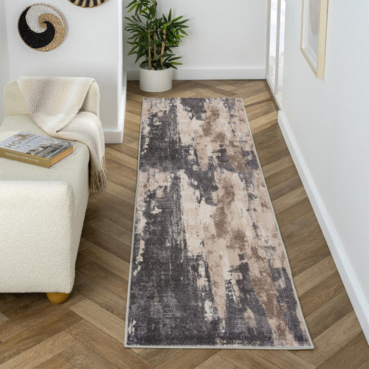 Long gray rectangular rug on a wooden floor with a white wall and plant in the background