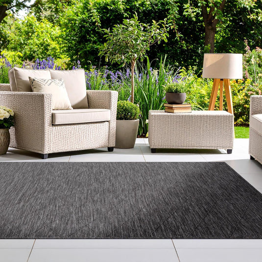 Outdoor patio with wicker furniture, rug, and garden view